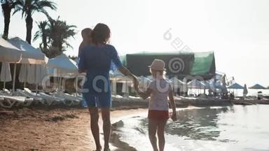 幸福的家庭母亲和两个孩子在海滩度假。 日落时分，母亲和两个孩子在海里